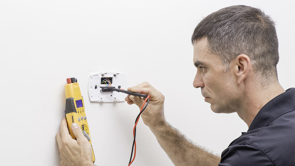 Electricista reparando cableado de termostato suelto