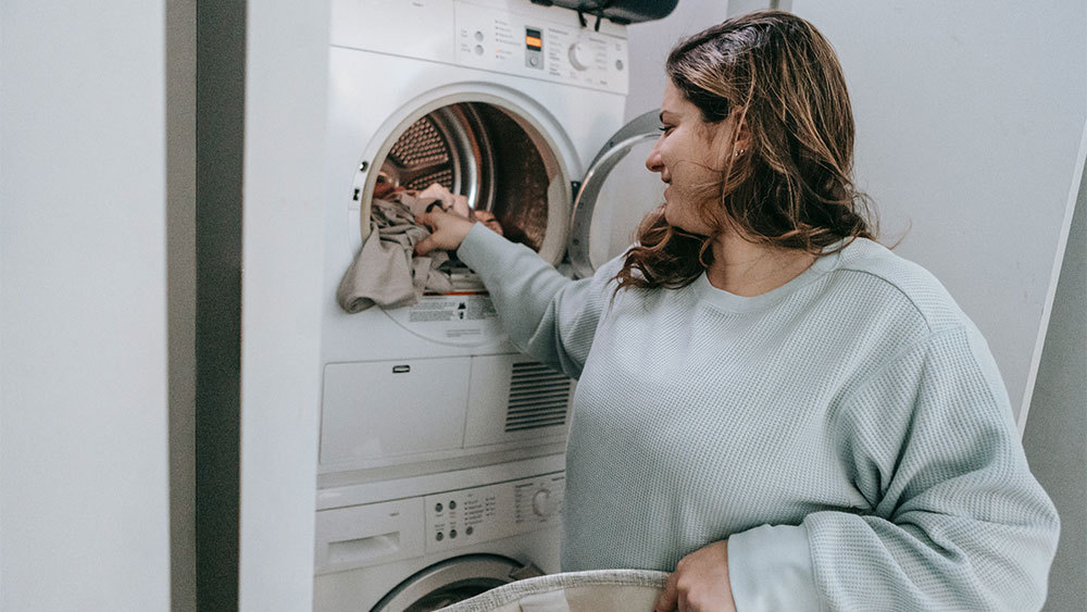 Mujer lavando ropa en agua fría para ahorrar en facturas de calefacción 