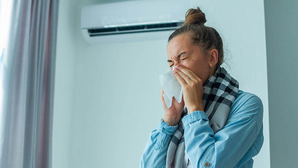 Mujer estornuda porque el crecimiento de moho en su aire acondicionado empeora sus problemas de alergia